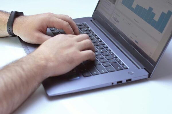 A marketer managing paid ads for real estate course creators by optimizing campaign settings on a laptop.
