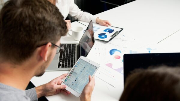 A person using a tablet to monitor real estate coaching lead generation strategies and campaign data.