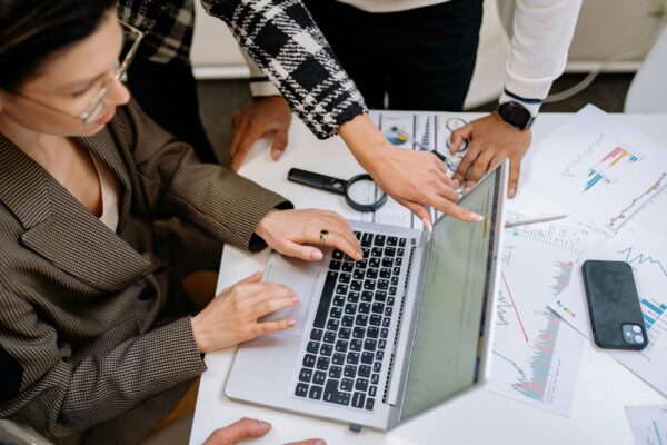 A team analyzing data charts and a laptop screen for webinar conversion optimization for real estate courses.