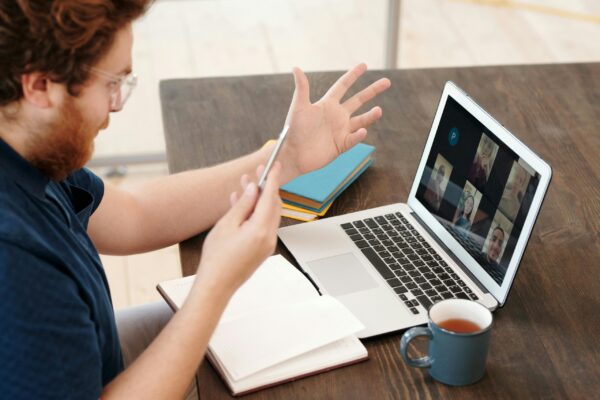 A man hosting a video call on a laptop, demonstrating webinar funnel marketing for real estate course enrollments.